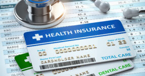 Image of a generic health insurance card and stethoscope laying on a test results spreadsheet