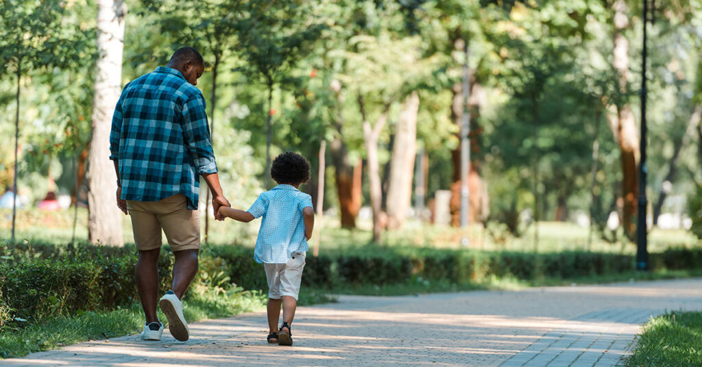 Black man with young son walking in the park