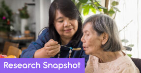 Daughter holds a spoon in front of elderly mother to help her eat soup.