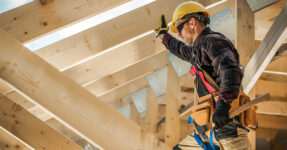 Home construction working shown standing in the roof frame of a house.