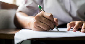 hand holding pen and writing on paper