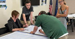 four people look over large spreadsheets