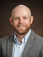 Thomas Krumel, PhD, Assistant Professor, NDSU, smiling in brown blazor