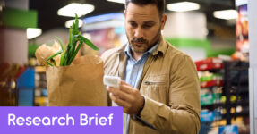 man holding a bag of groceries looks worried as he looks at the reciept